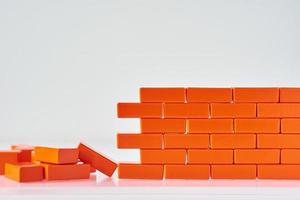 Broken wall made of toy blocks on a white background photo