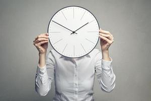 business woman covering her face with clock