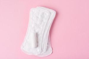 Sanitary pad and menstrual tampon on a pink background photo