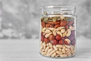 Layers of different types of nuts and seeds in a glass jar close up photo