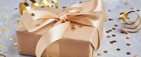 Gift box with golden bow and confetti, web banner photo