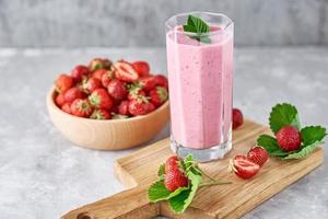 batido de fresa en un frasco de vidrio y fresas frescas con hojas foto