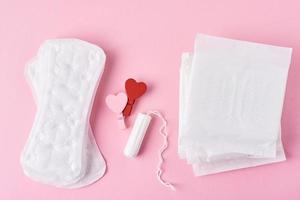 toalla sanitaria, tampón menstrual y corazón rojo de madera foto