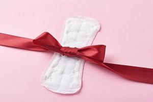 Sanitary pad and red ribbon on a pink background photo