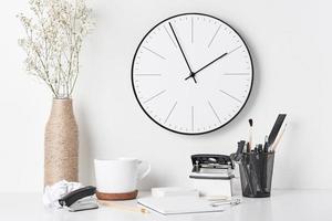 Office supplies and wall clock on white photo