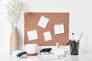 Cork board with office supplies on white background photo