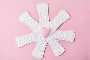 Sanitary pads and menstrual cup on a pink background photo