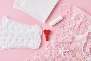 Sanitary pad, menstrual cup, tampon and panties on a pink background photo