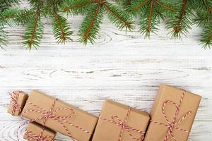 Pretty Christmas holiday border with decorative gifts tied with red ribbon and bows on fresh pine branches on a rustic wooden background with copyspace photo