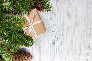 Wrapped Christmas gifts on dark rustic wooden table with pine cones and fir branches. With copy space for your text photo