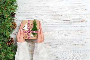 Christmas gift box wrapped in recycled paper, with ribbon bow, with ribbon on rustic background. Holiday concept photo