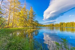 Beautiful early autumn scene of High Tatra lake. Colorful morning view of mountains sunlight, pine forest trees, idyllic sky reflection. Amazing nature landscape. Hiking adventure, beauty outdoors photo