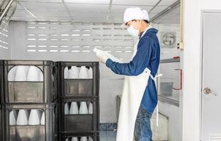 Young man worker or quality inspector in workwear and with a protective mask on his face working in checking bottled drinking water in drink water factory before shipment.drinking water business photo