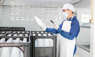 Young man worker or quality inspector in workwear and with a protective mask on his face working in checking bottled drinking water in drink water factory before shipment.drinking water business photo