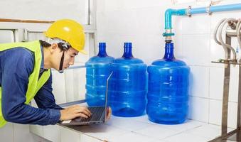 engineer working in drink water factory using a tablet computer to check and repair boiler water to the water system  in factory photo