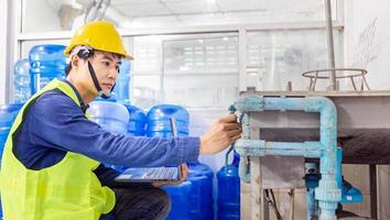 engineer working in drink water factory using a tablet computer to check and repair boiler water to the water system  in factory photo