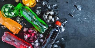 Top view  lot of bottles Soft drinks in colorful and flavorful  on the table, Glasses with sweet drinks with ice cubes photo