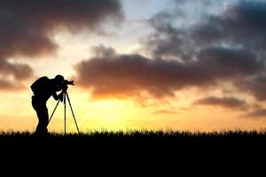 fotógrafo profesional tomando fotografías con cámara y trípode en un hermoso prado. foto