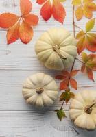 Autumn leaves and pumpkins over old wooden background photo