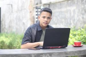 Atractivo joven asiático usando una laptop en un espacio de trabajo conjunto con cara feliz foto