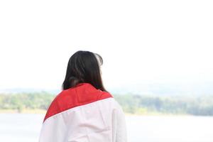 bella joven asiática que lleva la bandera indonesia con una cara alegre foto