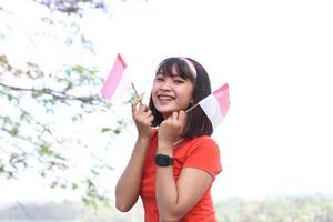 beautiful young asian woman carrying the indonesian flag with a cheerful face photo