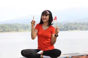beautiful young asian woman carrying the indonesian flag with a cheerful face photo