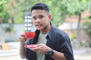 ASIAN YOUNG MAN DRINKING COFFEE IN THE MORNING photo