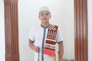 Young asian muslim praying in the mosque carrying a prayer mat photo