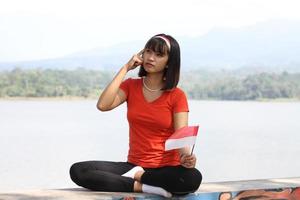 beautiful young asian woman carrying the indonesian flag with a cheerful face photo