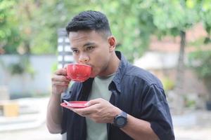 ASIAN YOUNG MAN DRINKING COFFEE IN THE MORNING photo