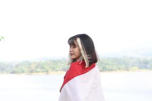 bella joven asiática que lleva la bandera indonesia con una cara alegre foto