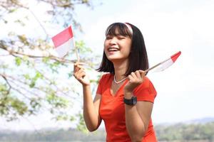 bella joven asiática que lleva la bandera indonesia con una cara alegre foto