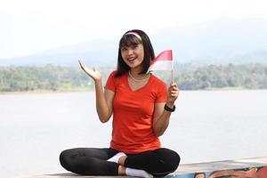 bella joven asiática que lleva la bandera indonesia con una cara alegre foto