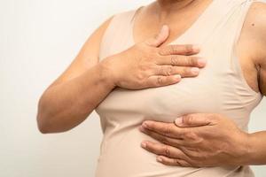 Asian woman patient checking and worry her breast, Breast Self Exam or BES, symbol of World Breast Cancer Day. photo