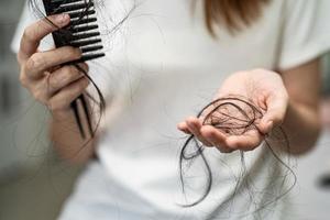 Asian woman have problem with long hair loss attach to comb brush. photo