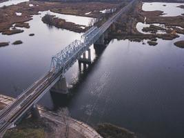 vista aérea de un cuerpo de agua con un puente ferroviario de metal sobre una base de hormigón. foto