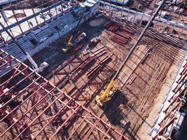 A mobile crane lifting metal beams onto the frame of a building. photo