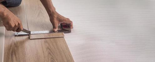 A technician is cutting luxury vinyl floor tiles with a cutter to lay the floor before placing it on the leveling foam. photo