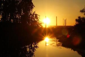 la vista del atardecer sobre un río, un bosque y un cielo colorido. foto