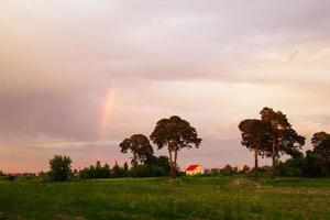 Tyumen, Russia. The rustic landscape with trees, colorful sky and rainbow at the sunset. photo