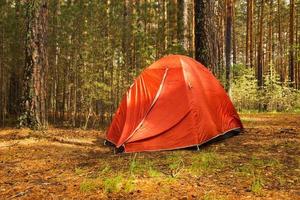 Siberia, Russia. An orange tent in a forest in a sunny day after rain. photo