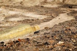 Old dirty glass bottle on a dry sandy soil. photo