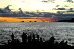 río de janeiro, rj, brasil, 2022 - personas en silueta miran la puesta de sol en arpoador rock, playa de ipanema foto