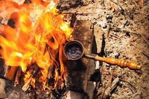 Metal cezve with hot coffee on a bonfire, top view. photo