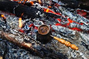 Metal cezve with hot coffee on a bonfire, top view. photo