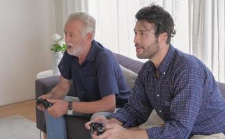 Two of caucasian old father and son family are enjoy to playing game console together in living room sofa on holiday. photo