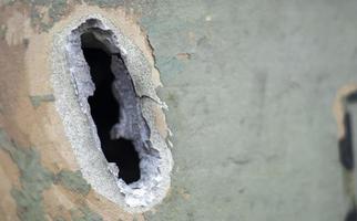 Hole or hole, armor deformation from a projectile close-up. Damaged armor of a Russian armored personnel carrier by shell fragments. War in Ukraine. Russian combat vehicle with holes in the armor. photo