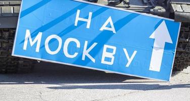 señal de carretera azul con letras blancas cerca del tanque, en el territorio del museo nacional de historia de ucrania. la guerra de rusia contra ucrania. traducción, a moscú. foto