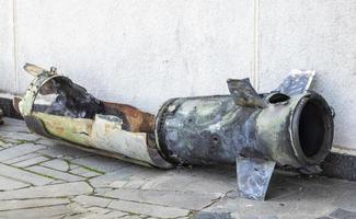 A metal fragment of a military rocket lies on the ground after the shelling of a civilian home. Rocket fire on the city and the horror of war. Ukraine war. The projectile is on the ground. photo